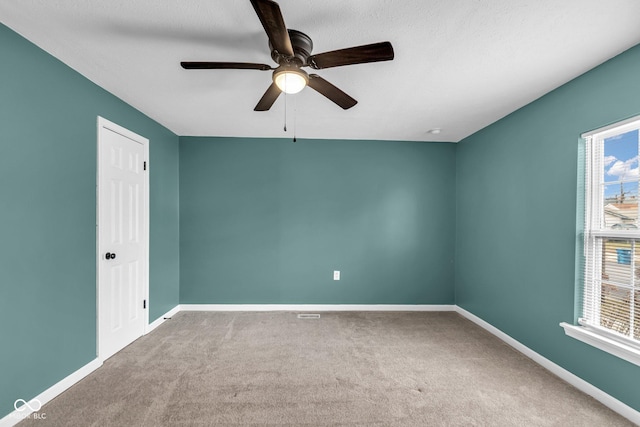 empty room featuring carpet flooring, ceiling fan, a textured ceiling, and baseboards