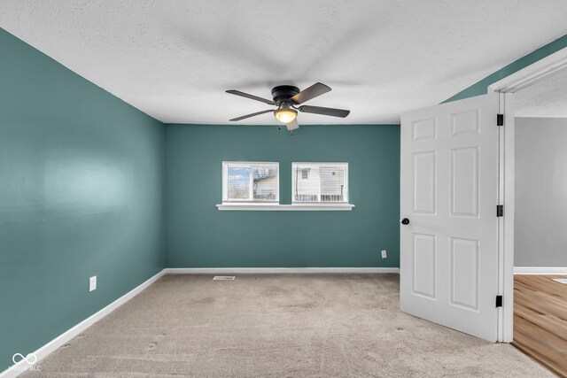 unfurnished room featuring carpet, ceiling fan, a textured ceiling, and baseboards