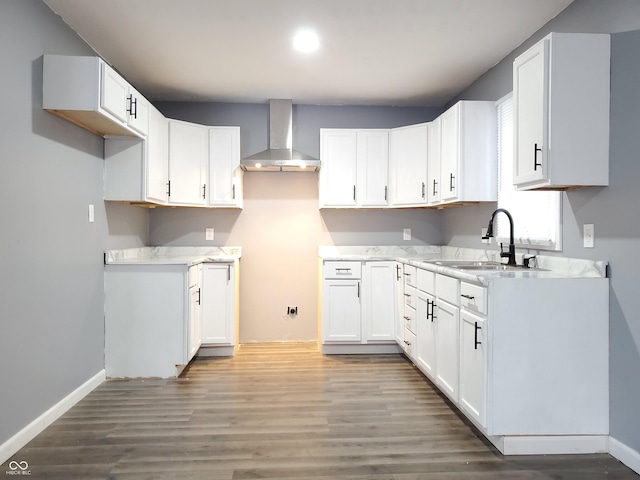 kitchen with hardwood / wood-style floors, white cabinetry, wall chimney exhaust hood, and sink