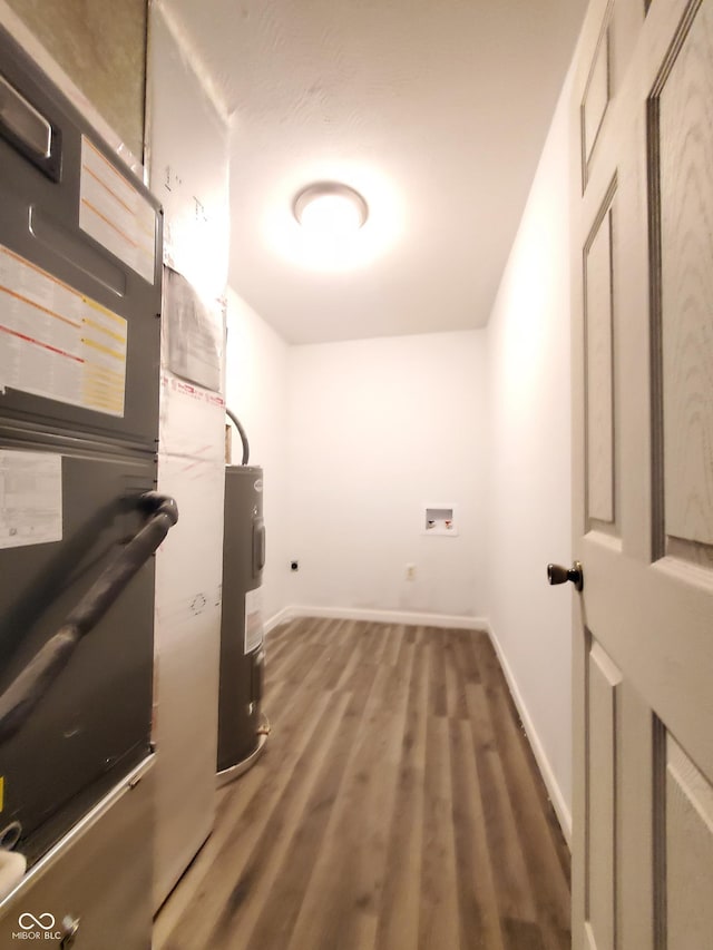 laundry area with dark hardwood / wood-style flooring and water heater