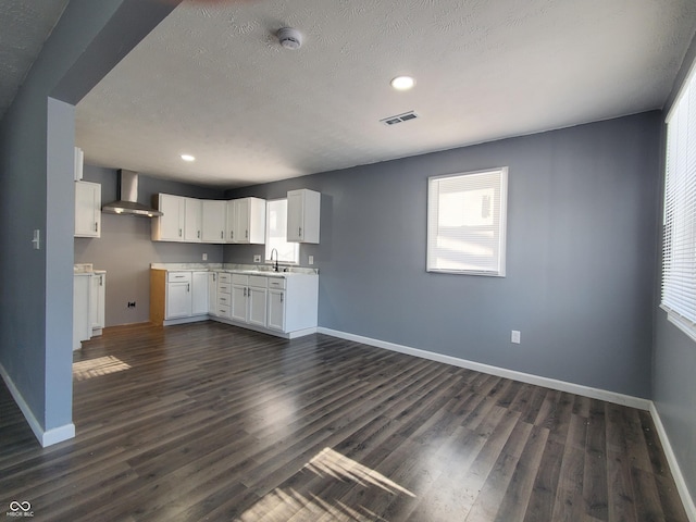 kitchen with white cabinets, a textured ceiling, dark hardwood / wood-style flooring, and wall chimney range hood