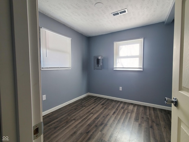 spare room featuring a wall mounted AC, dark hardwood / wood-style floors, and a textured ceiling