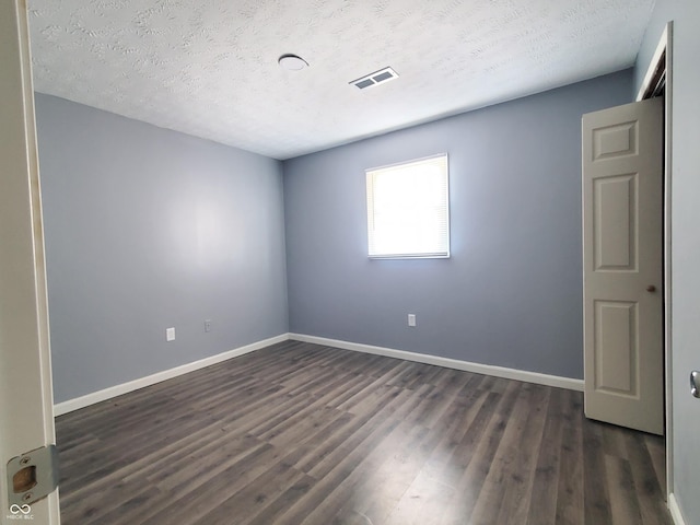 empty room featuring a textured ceiling and dark wood-type flooring