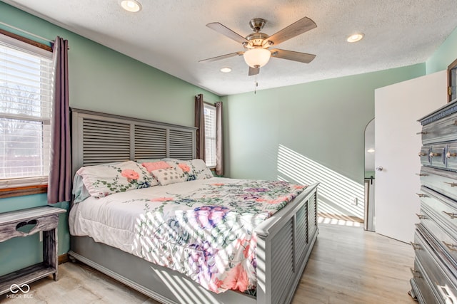 bedroom with light wood-type flooring, a textured ceiling, and ceiling fan