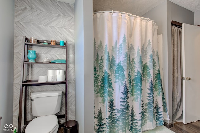 bathroom with a shower with shower curtain, toilet, and a textured ceiling