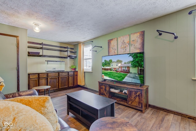 living room with wooden walls, light hardwood / wood-style floors, and a textured ceiling