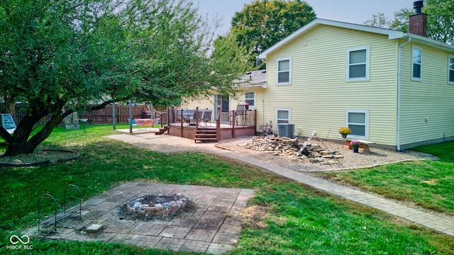 rear view of house with a fire pit, a patio area, a wooden deck, and a lawn