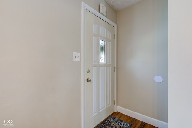 doorway to outside featuring a textured ceiling and dark wood-type flooring