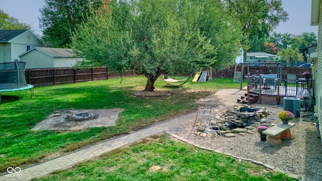 view of yard featuring a fire pit, a deck, a trampoline, a playground, and cooling unit