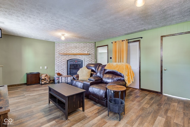 living room featuring hardwood / wood-style floors, a textured ceiling, and a brick fireplace