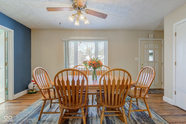 dining space with hardwood / wood-style flooring, ceiling fan, and a textured ceiling