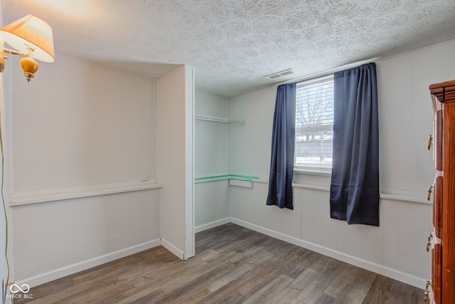 spare room featuring hardwood / wood-style floors and a textured ceiling