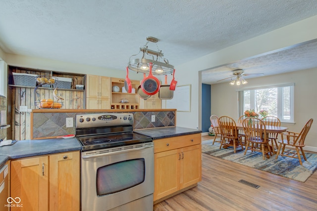 kitchen featuring decorative backsplash, light hardwood / wood-style floors, stainless steel electric range oven, and ceiling fan