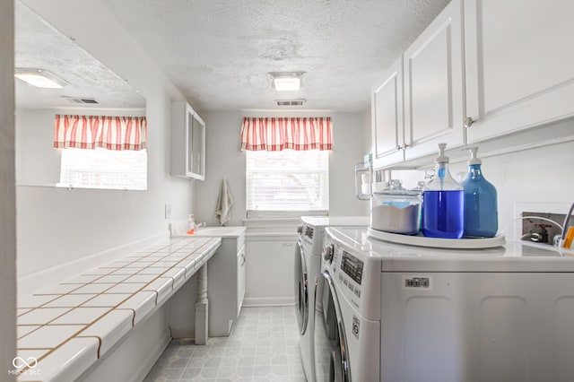 laundry room with cabinets, a textured ceiling, and independent washer and dryer