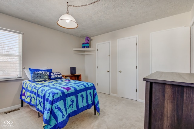 bedroom featuring light colored carpet and a textured ceiling