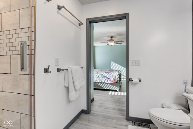 bathroom with ceiling fan, hardwood / wood-style floors, a shower with door, and toilet