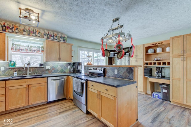 kitchen featuring sink, backsplash, pendant lighting, light hardwood / wood-style floors, and appliances with stainless steel finishes