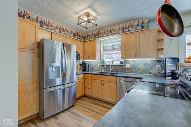 kitchen featuring sink, light brown cabinets, stainless steel appliances, decorative backsplash, and light wood-type flooring