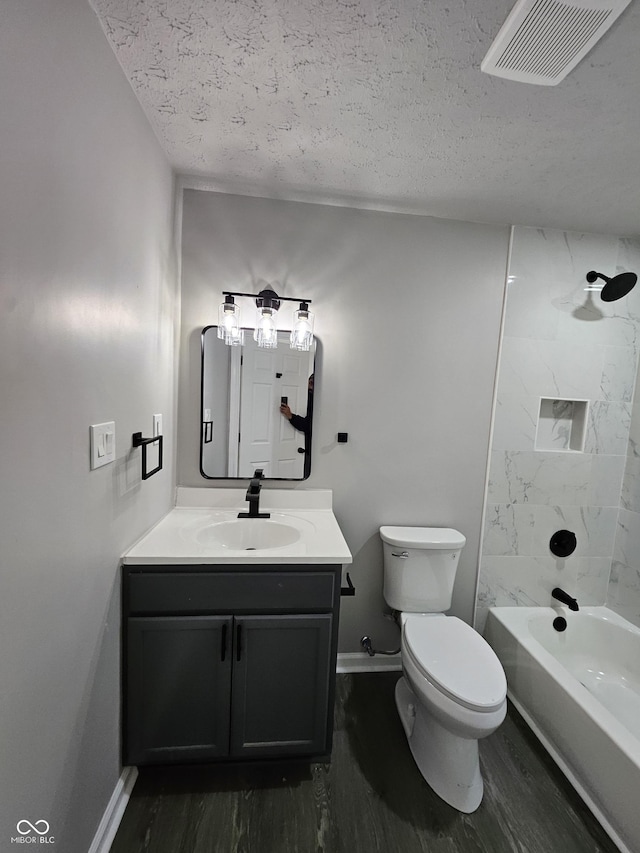 full bathroom with vanity, toilet, a textured ceiling, and tiled shower / bath combo