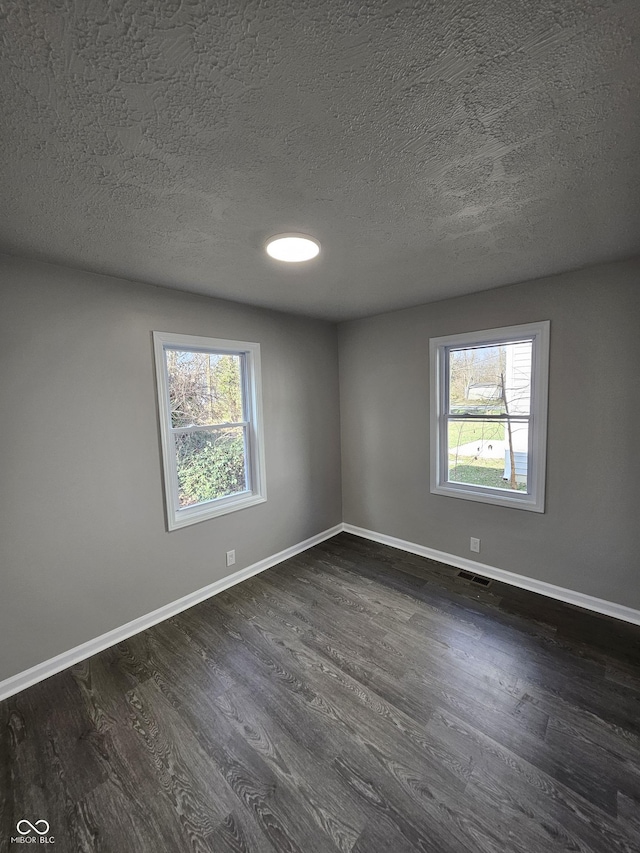 unfurnished room with a textured ceiling and dark hardwood / wood-style floors