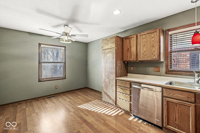 kitchen featuring light wood-type flooring, ceiling fan, sink, decorative light fixtures, and dishwasher