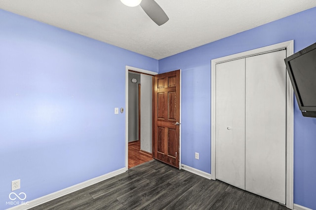 unfurnished bedroom with dark hardwood / wood-style flooring, a closet, and ceiling fan