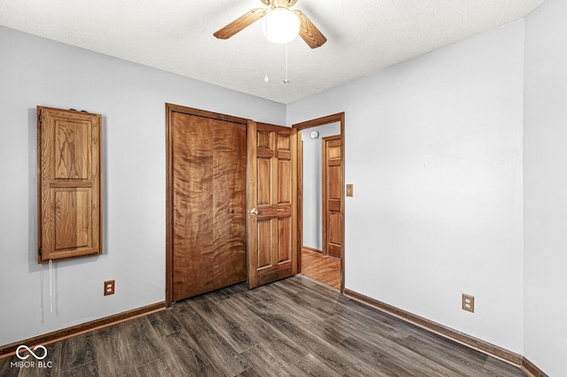 unfurnished bedroom featuring a closet, ceiling fan, dark hardwood / wood-style flooring, and a textured ceiling