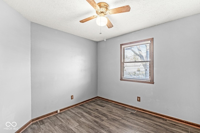 empty room with ceiling fan, dark wood-type flooring, and a textured ceiling