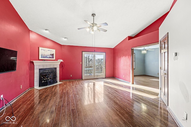 unfurnished living room featuring hardwood / wood-style floors, lofted ceiling, and a tiled fireplace