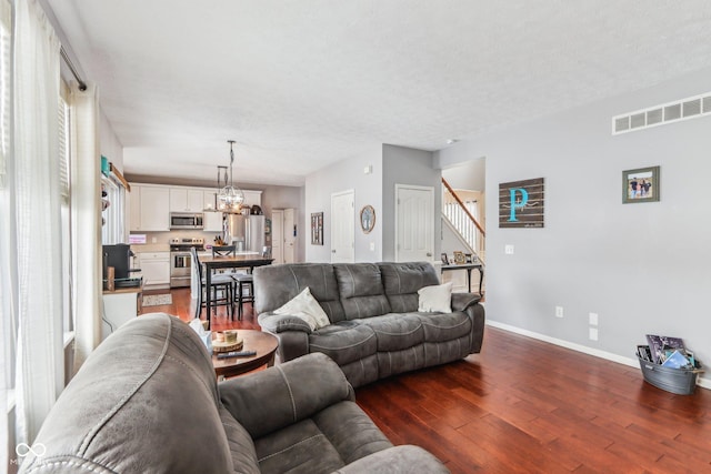 living room featuring dark hardwood / wood-style floors, a notable chandelier, and a textured ceiling