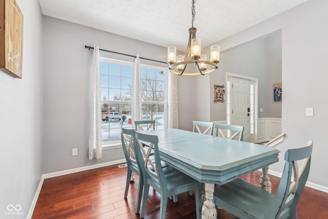 dining room with dark hardwood / wood-style flooring, a textured ceiling, and a notable chandelier