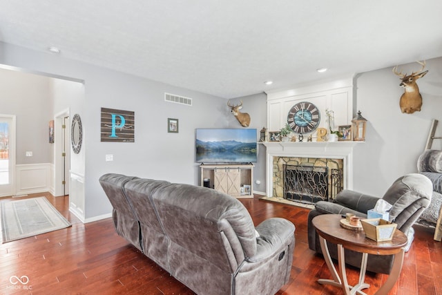 living room with a stone fireplace and dark hardwood / wood-style floors