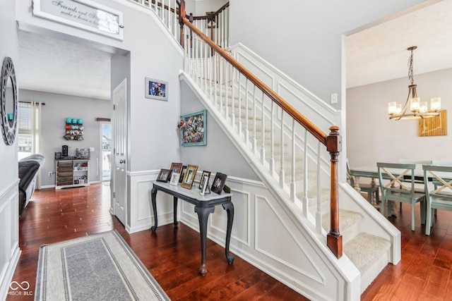 stairs with a high ceiling, wood-type flooring, and a chandelier