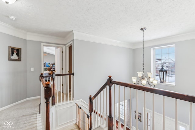 hallway with crown molding, carpet flooring, a chandelier, and a textured ceiling