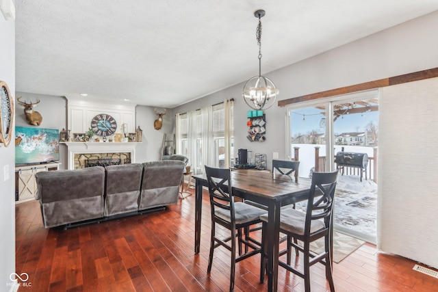 dining room with a notable chandelier, a fireplace, dark hardwood / wood-style floors, and plenty of natural light