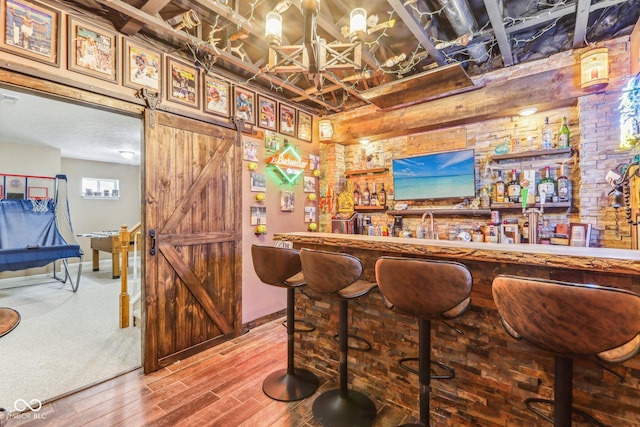 bar featuring a barn door and hardwood / wood-style floors