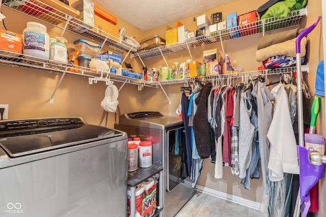 laundry room with tile patterned floors, washing machine and dryer, and a textured ceiling