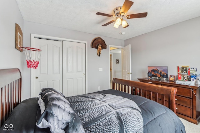 carpeted bedroom with ceiling fan, a textured ceiling, and a closet