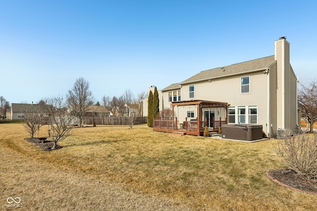 rear view of property featuring a pergola, a wooden deck, a yard, and a hot tub