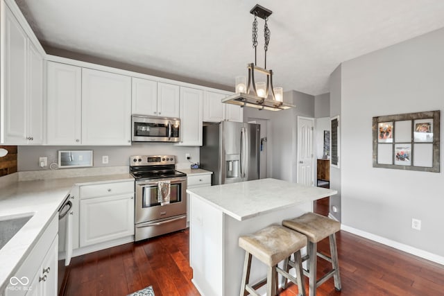 kitchen with a kitchen island, appliances with stainless steel finishes, white cabinets, dark hardwood / wood-style flooring, and hanging light fixtures