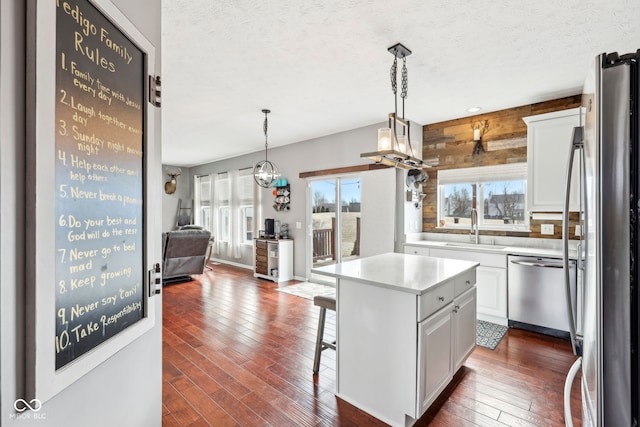 kitchen featuring pendant lighting, appliances with stainless steel finishes, a center island, and white cabinets