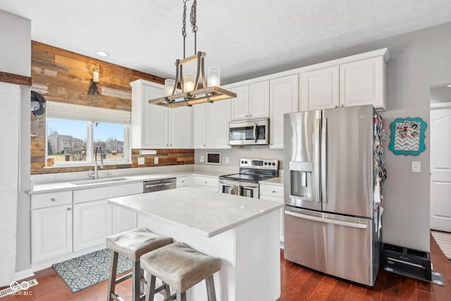 kitchen featuring stainless steel appliances, a kitchen island, sink, and white cabinets