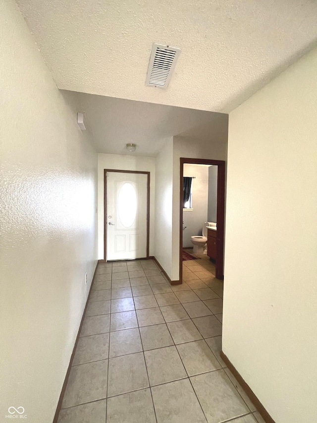 corridor with light tile patterned floors and a textured ceiling