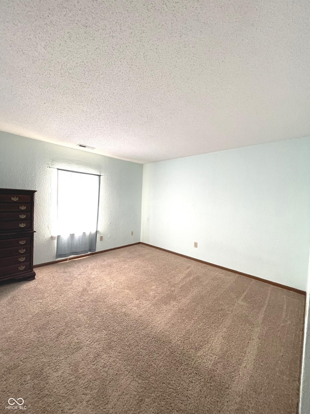 empty room with carpet and a textured ceiling