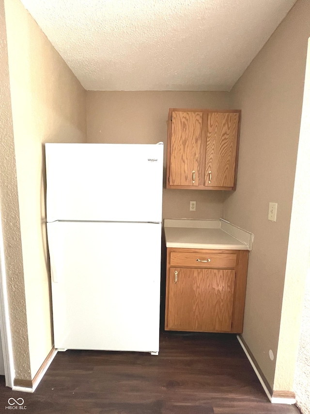 kitchen featuring a textured ceiling, white refrigerator, and dark hardwood / wood-style floors