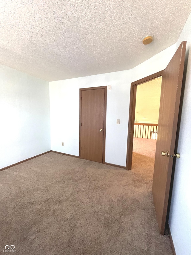 spare room featuring light colored carpet and a textured ceiling