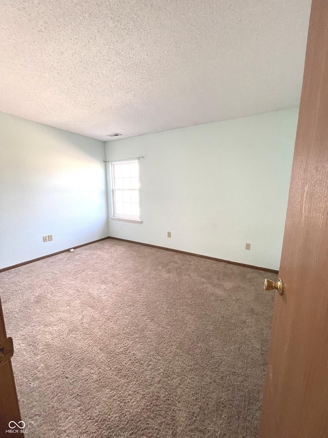 carpeted spare room featuring a textured ceiling