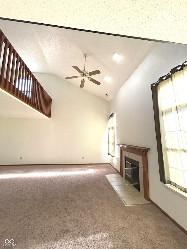 unfurnished living room with ceiling fan, a textured ceiling, vaulted ceiling, light carpet, and a fireplace