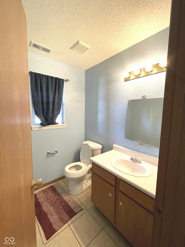 bathroom with tile patterned flooring, vanity, a textured ceiling, and toilet