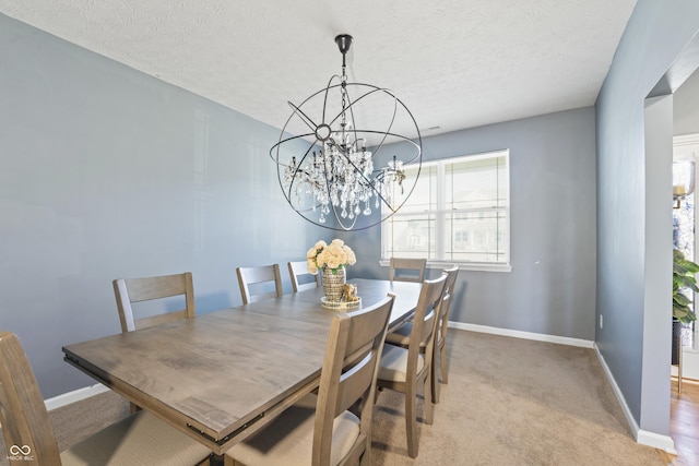 carpeted dining area featuring a chandelier and a textured ceiling